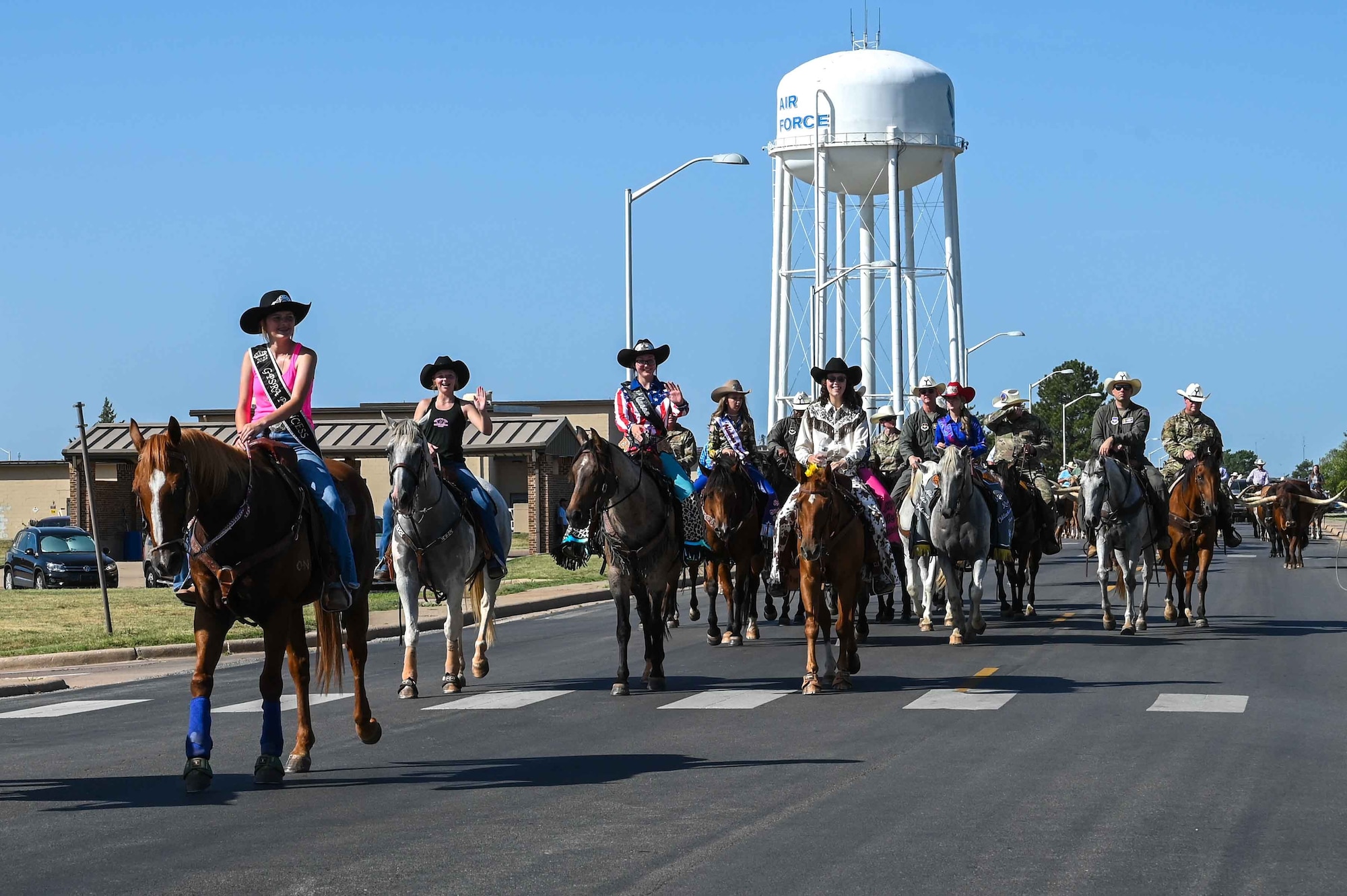The 2023 Miss Oklahoma Rodeo Queens wave at Airmen and families during the 25th Annual Cattle Drive at Altus Air Force Base (AFB), Oklahoma, Aug. 24, 2023. Altus AFB works with the local community to host the cattle drive annually. (U.S. Air Force photo by Airman 1st Class Kari Degraffenreed)