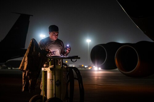 Service member conducting maintenance on the flight line at night