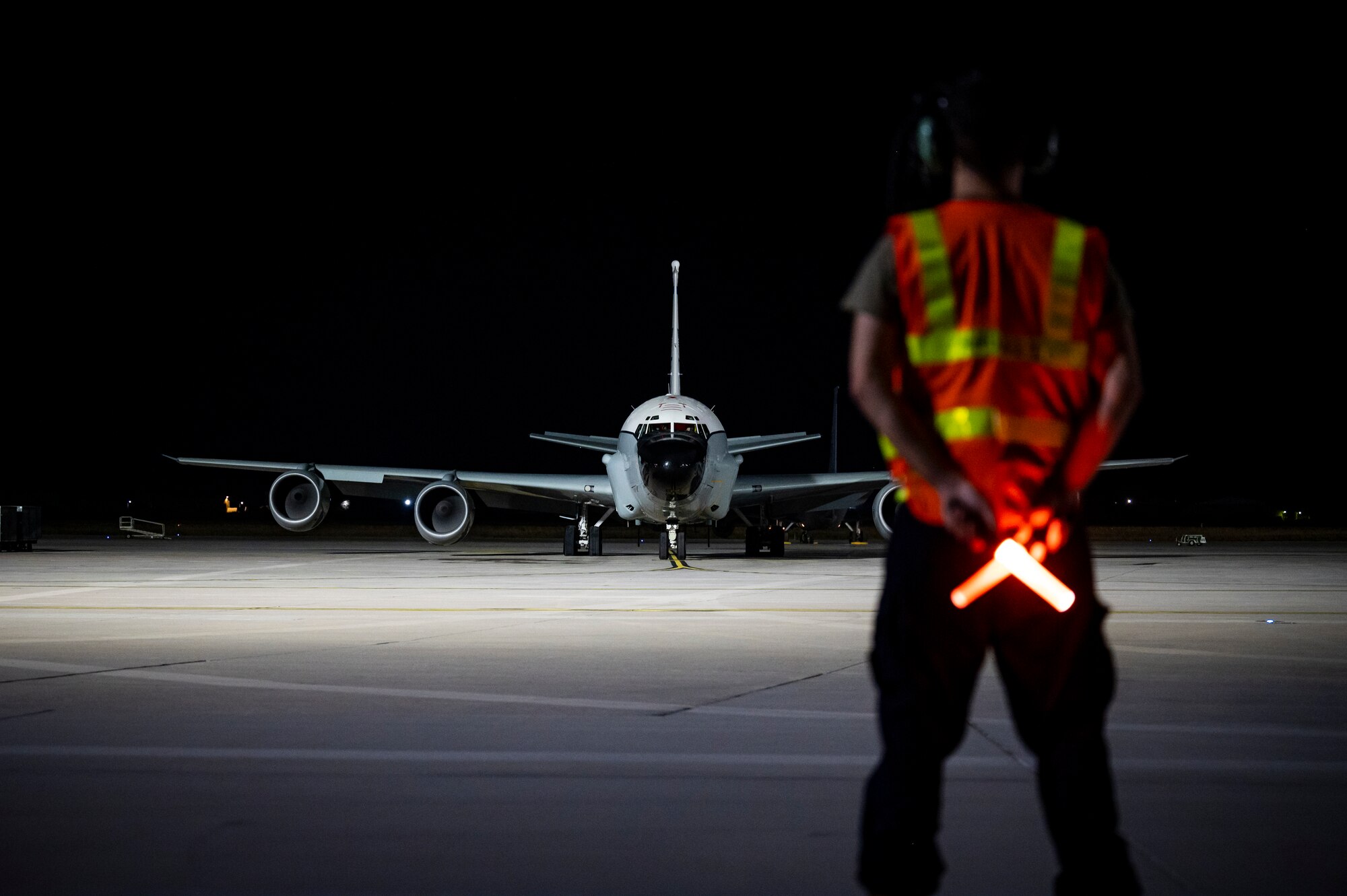 Service member standing on the flight line at night with an aircraft in the background