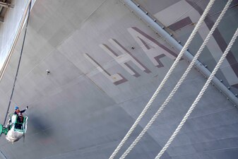 Sailors sand the hull of USS Tripoli (LHA 7) at Naval Base San Diego.