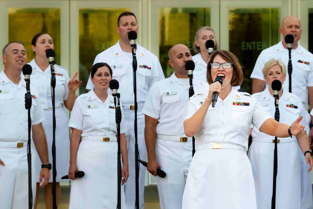 Sailors sing into microphones.