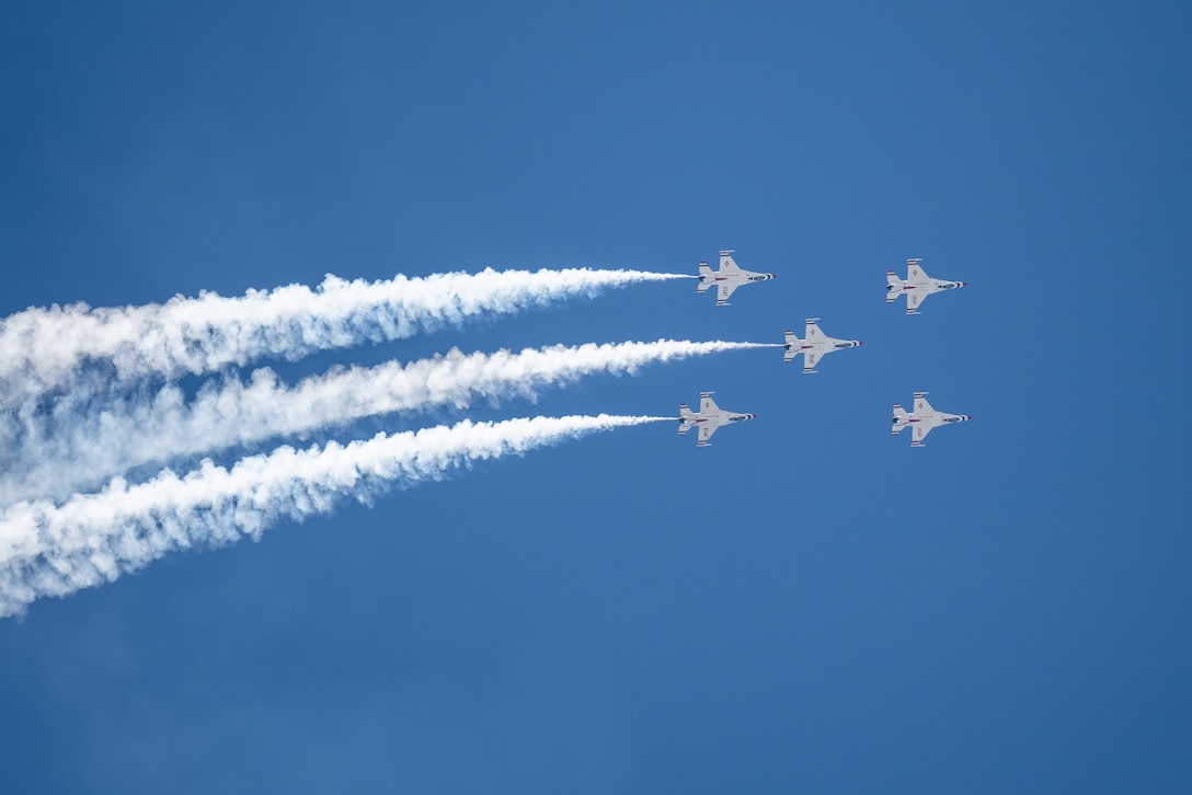 Five aircraft fly in formation during daylight creating vapor trails.