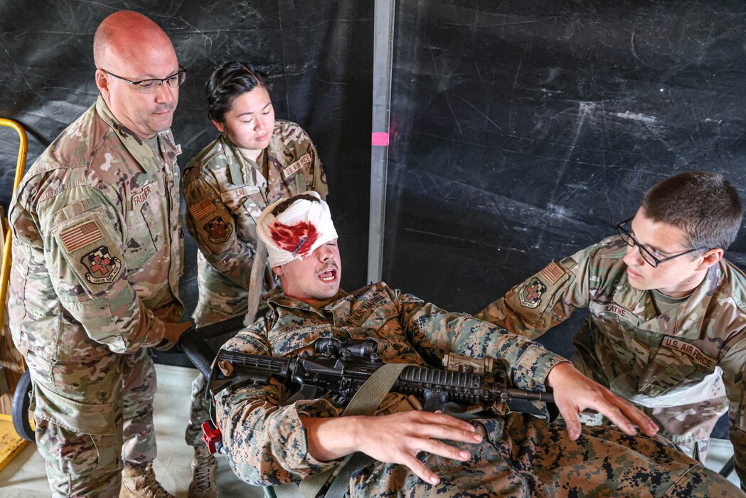 U.S. Air Force Master Sgt. Brian Faulkner, left, Staff Sgt. Kimberly Lai, center, and Senior Airman Cameron Layne, right, all aerospace medical technicians with the Michigan National Guard’s 127th Medical Group, simulate transporting patients for evacuation during an Exercise Northern Strike 23 joint medical training event at the Grayling Army Air Field, Grayling, Michigan, Aug. 15, 2023. NS23 is one of the National Guard’s largest annual joint, readiness-producing exercises, held within the Michigan National Guard’s, “National All-Domain Warfighting Center,” and designed to challenge the training audience in a variety many ways, including contested sustainment/logistics. (U.S. Air National Guard photo by Tech. Sgt. Andrew Schumann