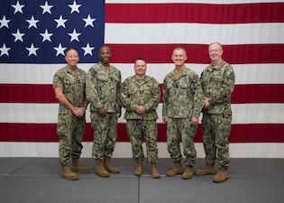 Top Leaders of the MyNavy HR Enterprise stand together for a group photo in front of American flag
