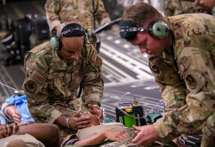 Aeromedical evacuation technicians from the 183rd Aeromedical Evacuation Squadron administer aid to a simulated patient during medical airlift evacuation training in Gulfport, Mississippi, July 20, 2023. The 183rd Aeromedical Evacuation Squadron conducted annual training with the 189th Medical Group, Arkansas ANG, U.S. Coast Guard New Orleans and Gulfport.