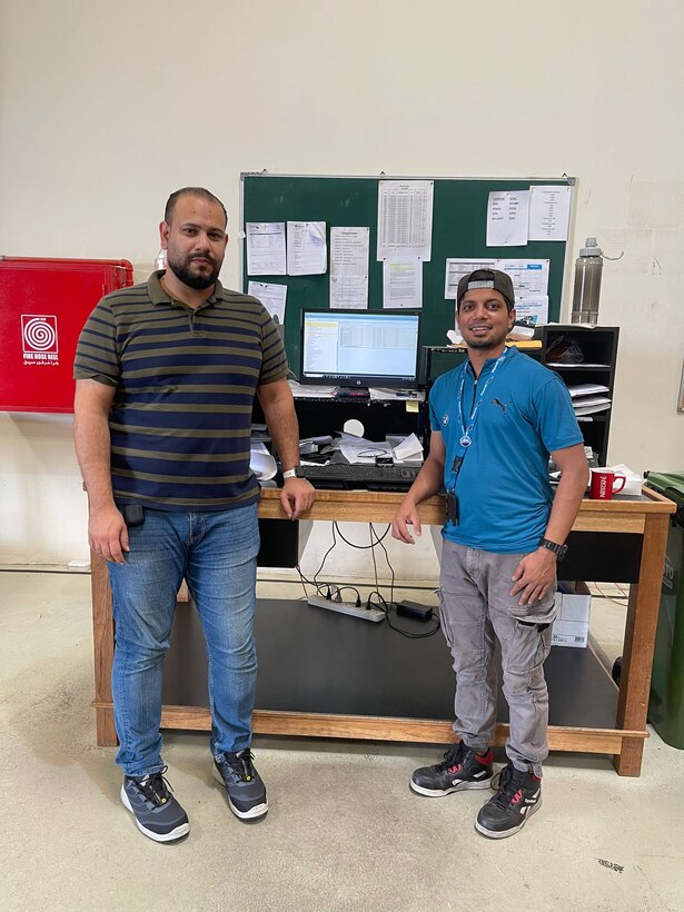 Two workers near a work station.