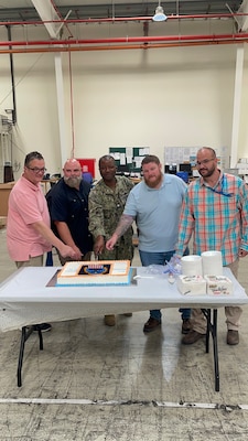 five people cutting into a cake