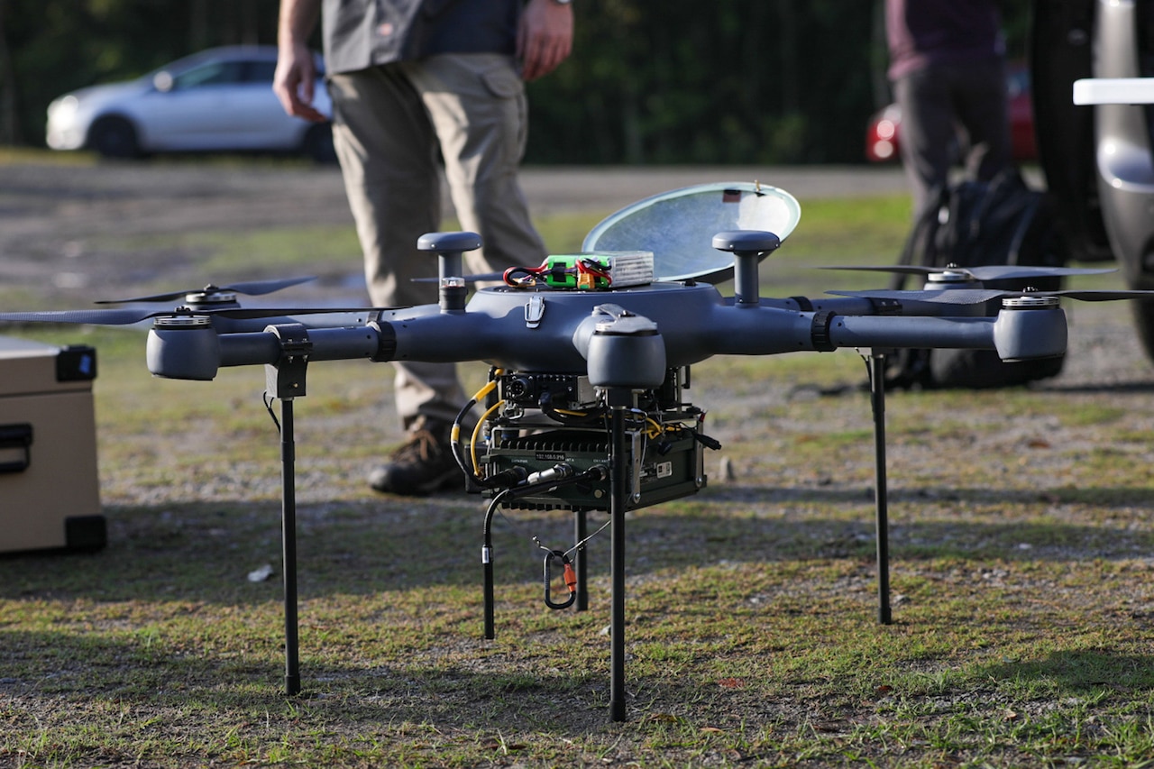 Soldiers test a drone in a field.