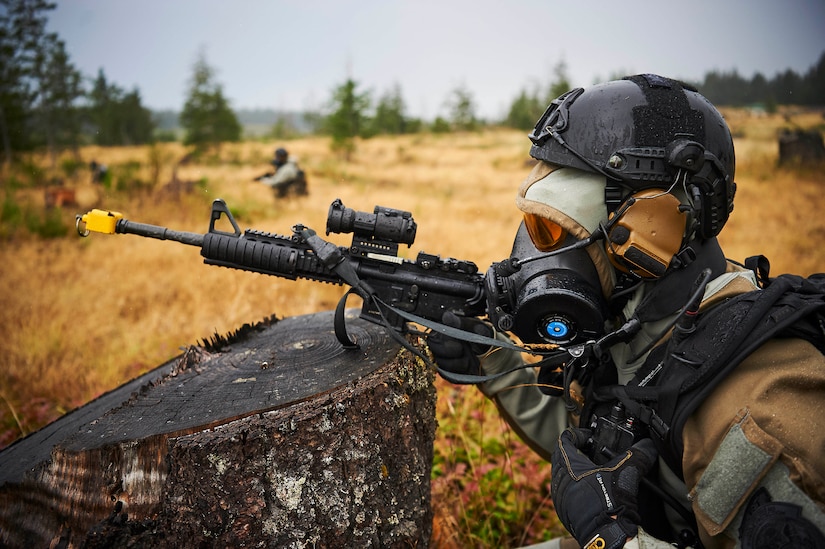 A service member wearing high-tech protective gear aims a weapon.