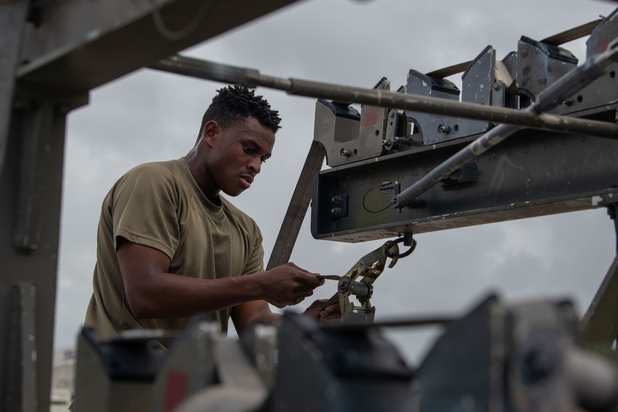 Technician secures straps on a munitions rack during a weapons load competition.
