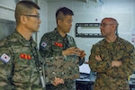 Republic of Korea Marine Corps 1st Lt. Rukhan Lee, an interpreter with ROK Marine Corps Headquarters, center, facilitates a conversation between U.S. Marine Corps Col. Andrew Gourgoumis, current operations officer with III Marine Expeditionary Force, right, and ROK Marine Corps Lt. Col. Jaemyoung Lee, an exercise planning officer with ROK Marine Corps Headquarters, left, in the Landing Force Operations Center aboard the USS Blue Ridge (LCC-19) in support of Ulchi Freedom Shield 23, August 25, 2023. U.S. 7th Fleet’s flagship USS Blue Ridge is in port at Fleet Activities Yokosuka in Yokosuka, Japan. Ulchi Freedom Shield is a defense-oriented exercise designed to strengthen the ROK-U.S. Alliance, enhance our combined defense posture, and strengthen security and stability on the Korean peninsula. Gourgoumis is a native of Boston.