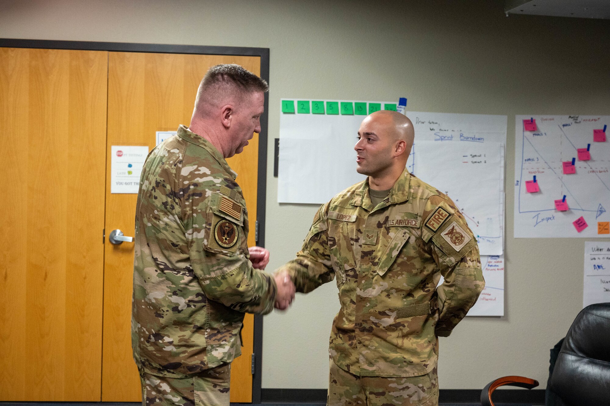 U.S. Air Force Chief Master Sgt. Chad Bickley, command chief of Air Education and Training Command, coins Senior Airman Carlos Lopez, 56th Civil Engineer Squadron firefighter, during a base visit, Aug. 18, 2023, at Luke Air Force Base, Arizona.