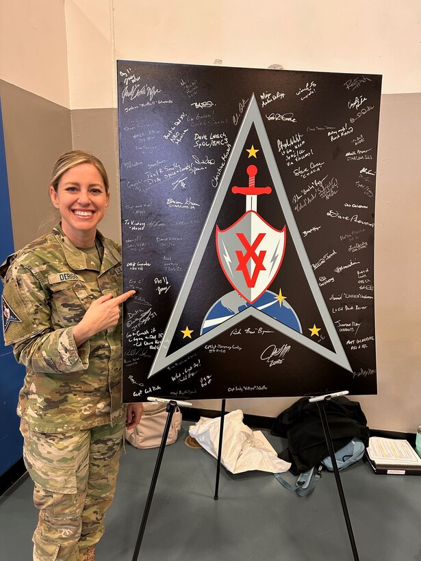 Woman in military uniform stands next to sign