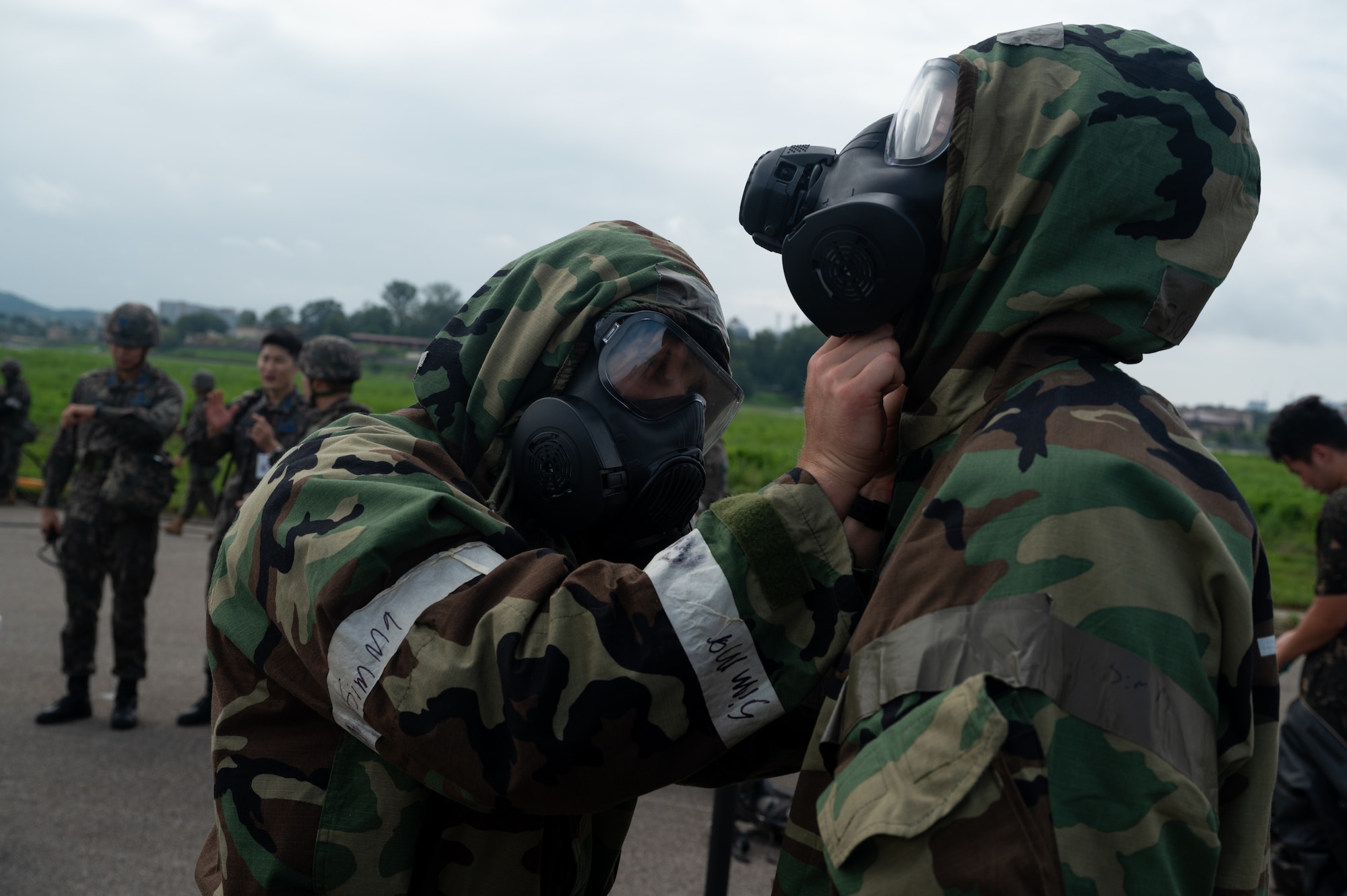 U.S. Air Force Airman William Dobyns, left, and Staff Sgt. David Gogev, 51st Civil Engineer Squadron emergency managers, adjust each other’s individual protective equipment while conducting a buddy check during combined forces chemical, biological, radiological and nuclear training with the 51st CES at Osan Air Base, ROK, Aug. 24, 2023. Dobyns and Gogev processed U.S. and ROK troops through a simulated decontamination line to ensure the safety of members that came into contact with hazardous materials. (U.S. Air Force photo by Airman 1st Class Chase Verzaal)