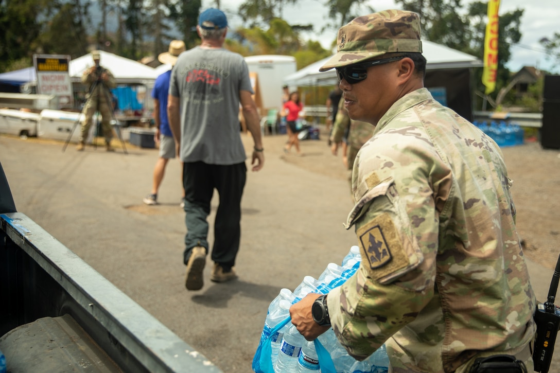 A soldier holds a case of bottled water.