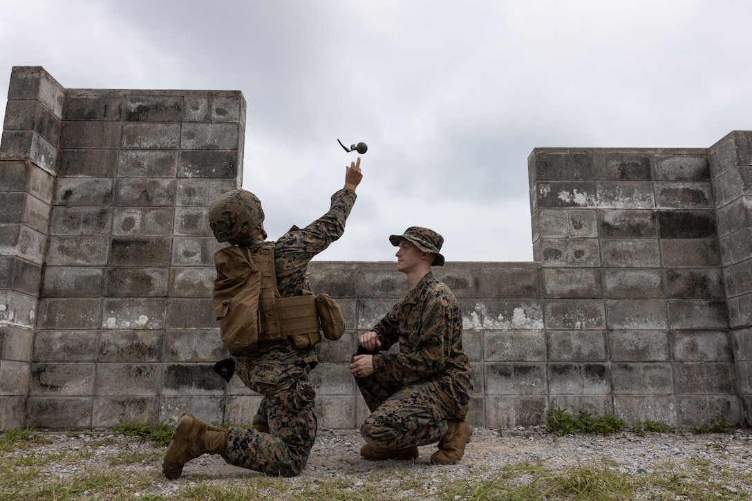 A Marine throws a practice grenade over a wall.