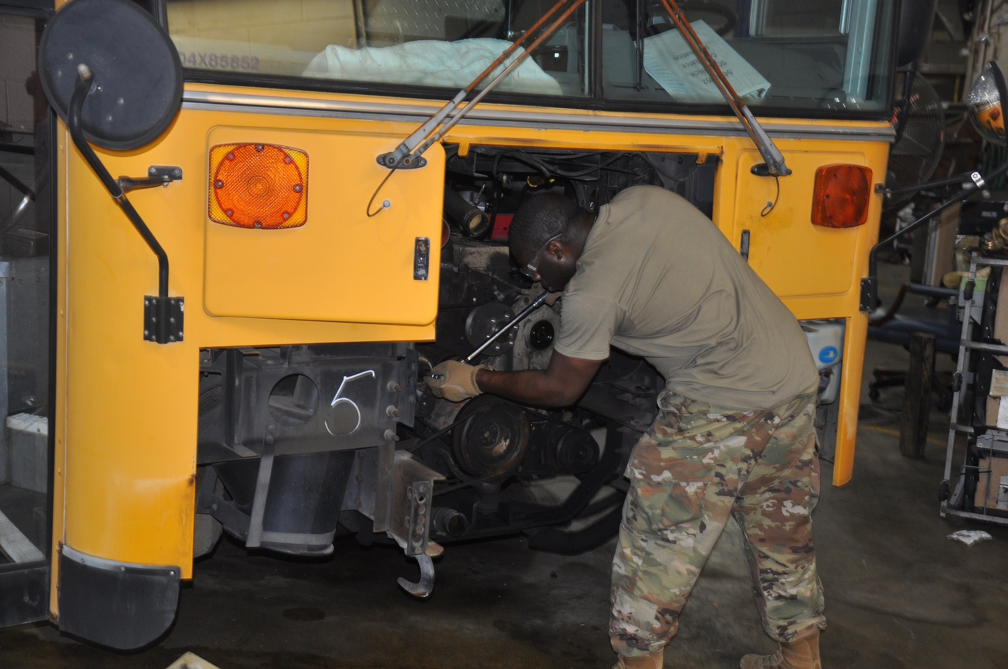 a person works on the engine of a school bus