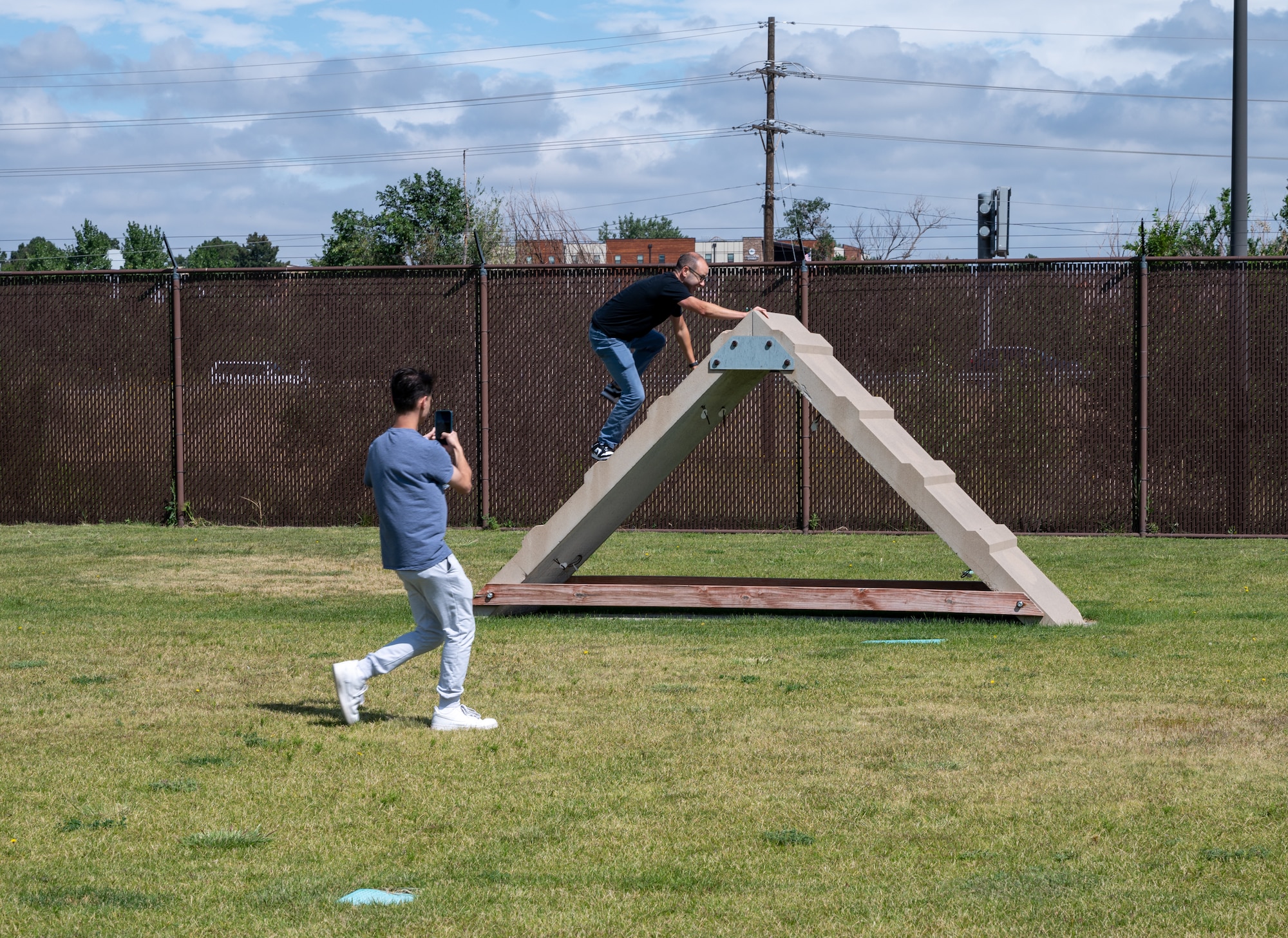 James Murray climbs a triangular tower used for training military working dogs while filming a video for social media.