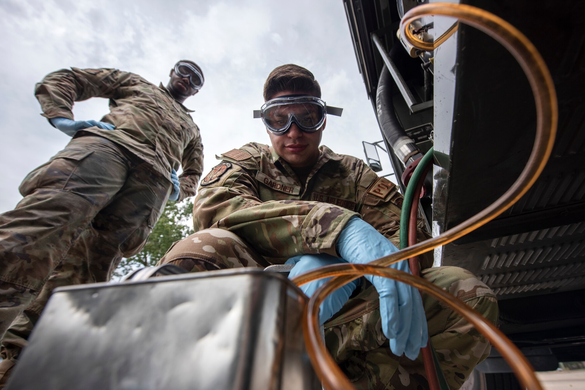 Staff Sgt. Dylan Gardner, center, 4th Logisitcs Readiness Squadron fuels laboratory NCOIC, and Airman 1st Class Adrian Morris, 4th LRS fuels laboratory fuels distribution operator, transfer fuel from fuel truck to a container in preparation for testing at Seymour Johnson Air Force Base, North Carolina, Aug. 10, 2023. Airmen assigned to the 4th LRS fuels lab are responsible for testing the cleanliness and quality of fuel used in ground and air operations to help ensure the safety of Airmen and assets when performing the day-to-day mission. (U.S. Air Force photo by Tech. Sgt. Christopher Hubenthal)