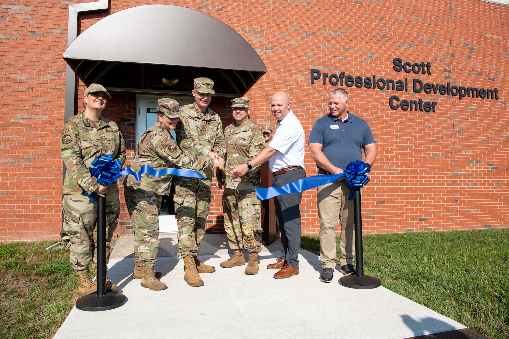A group of people cut a ribbon to open the new professional development center.