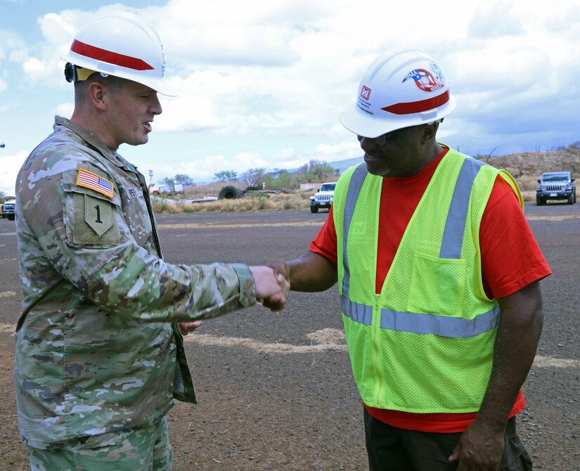Lt. Col. Ryan C. Pevey, commander, Honolulu District, U.S. Army Corps of Engineers presents a coin to Derrick McGee, a contract specialist from the Honolulu District Power Planning and Response Team on Maui, Aug. 28. The USACE is working with local, state and federal partners on a mission assignment from the Federal Emergency Management Agency in response to the Hawai’i Wildfires.
