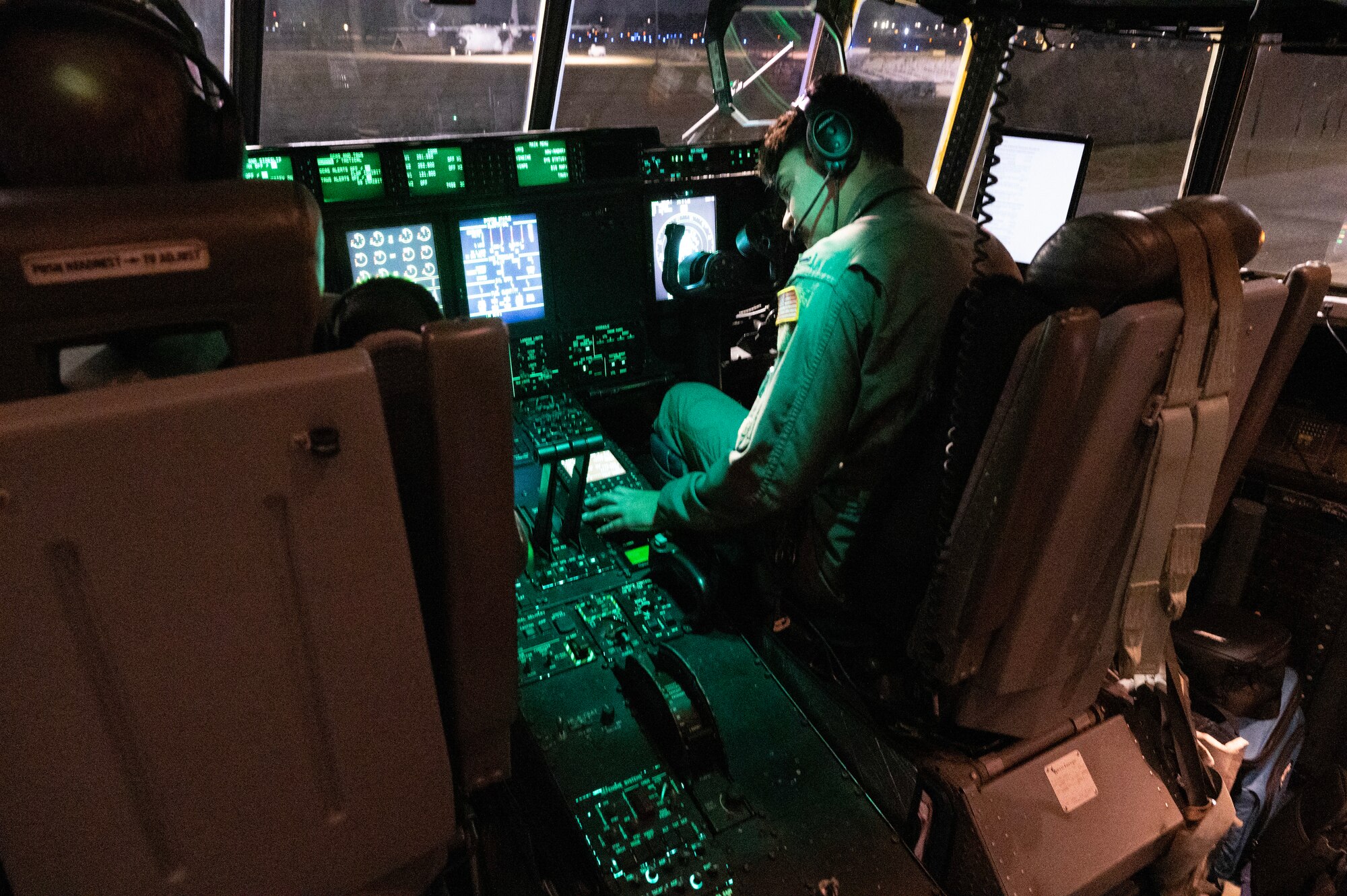 An Air Force pilot sits in the co-pilot chair and does a checklist