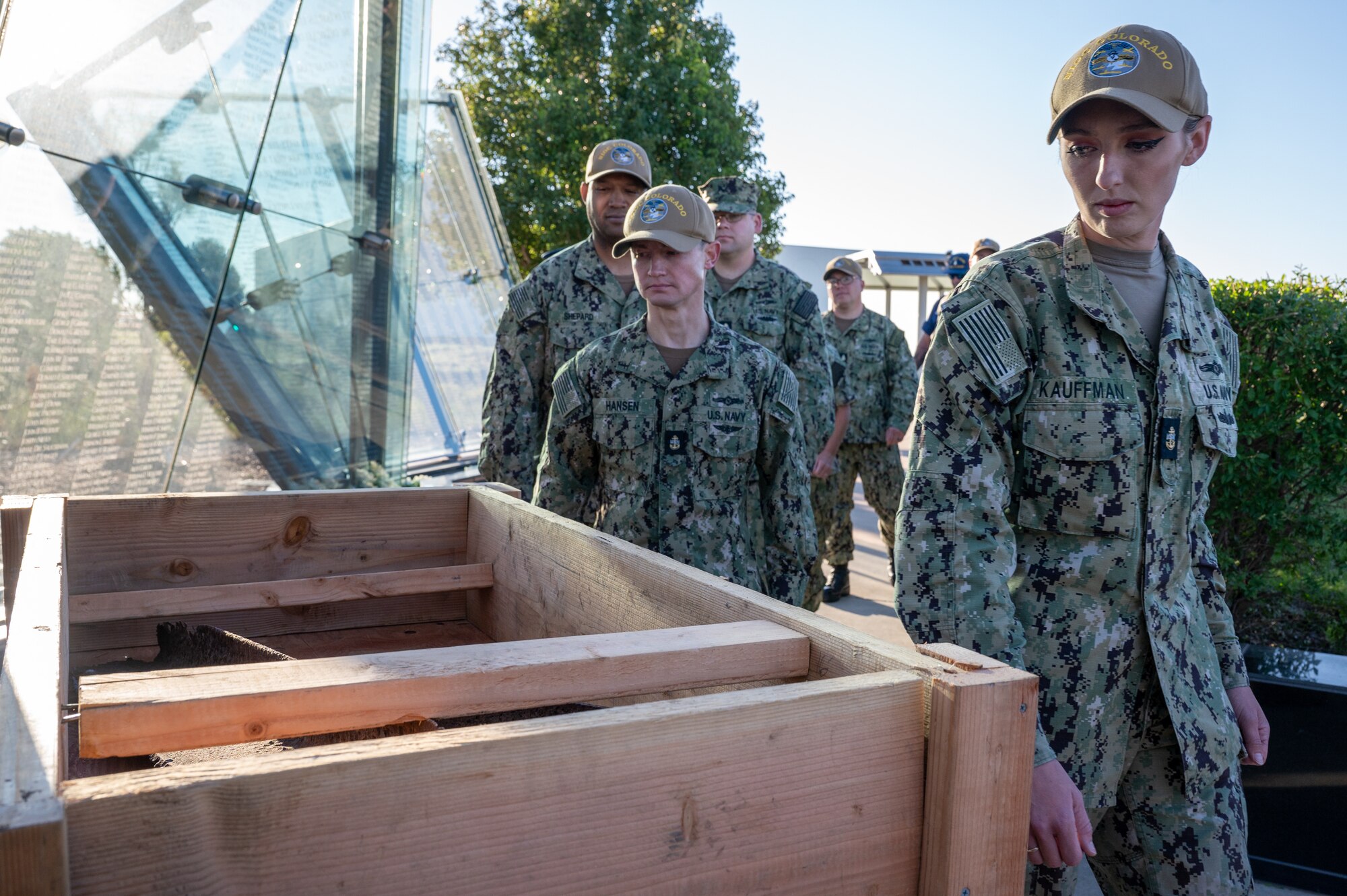 Sailors walk past a wooden box and look at it.