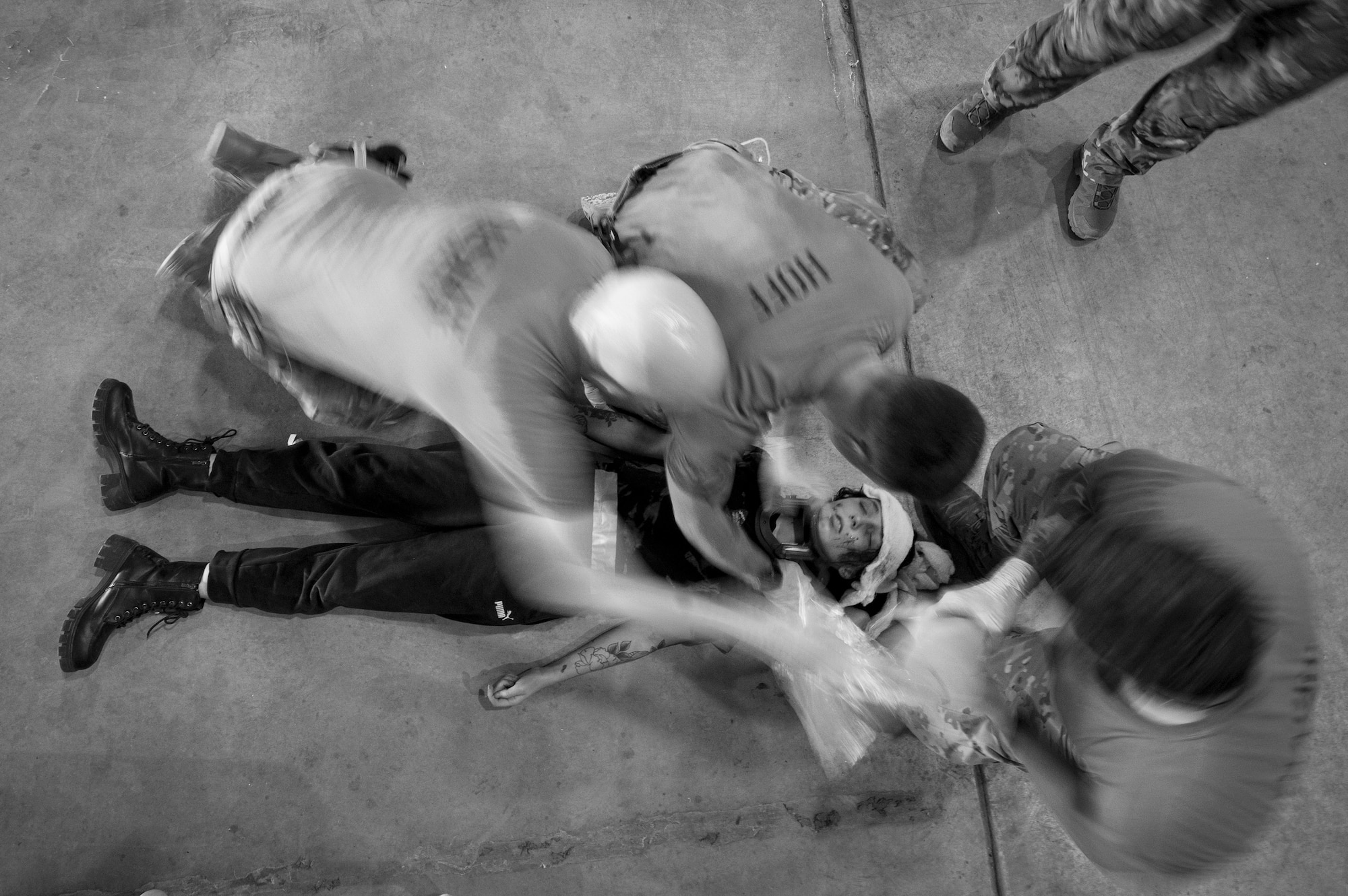 Three medics kneel over a patient on the ground as they provide assistance for head injuries.