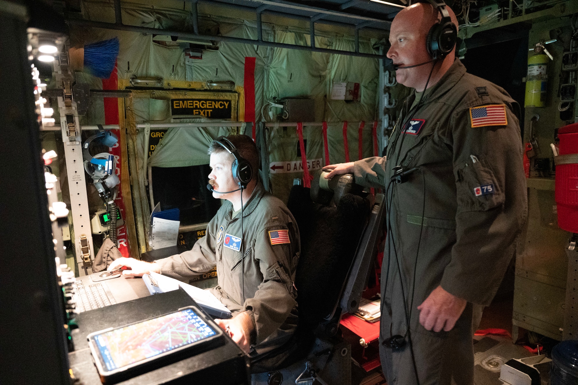 Two Air Force Reserve members check weather data on a WC-130J aircraft during a hurricane flight.