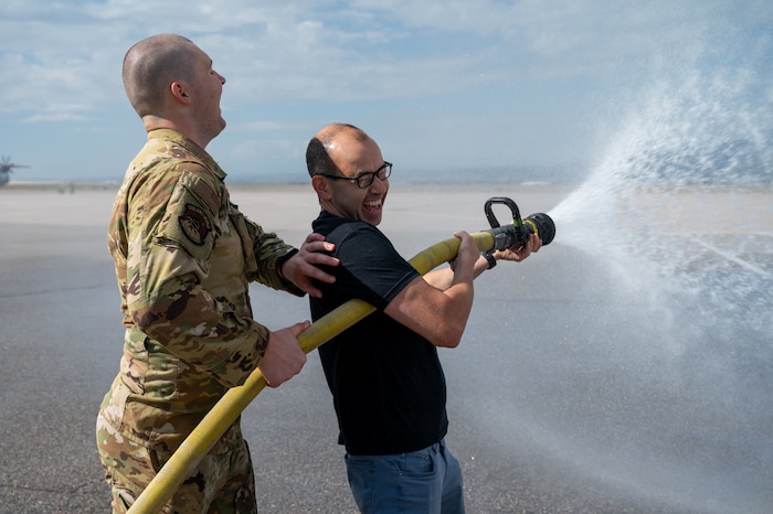 James Murray operates a firehose and laughs while getting splashed from the excess water.