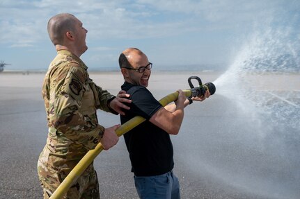 James Murray operates a firehose and laughs while getting splashed from the excess water.