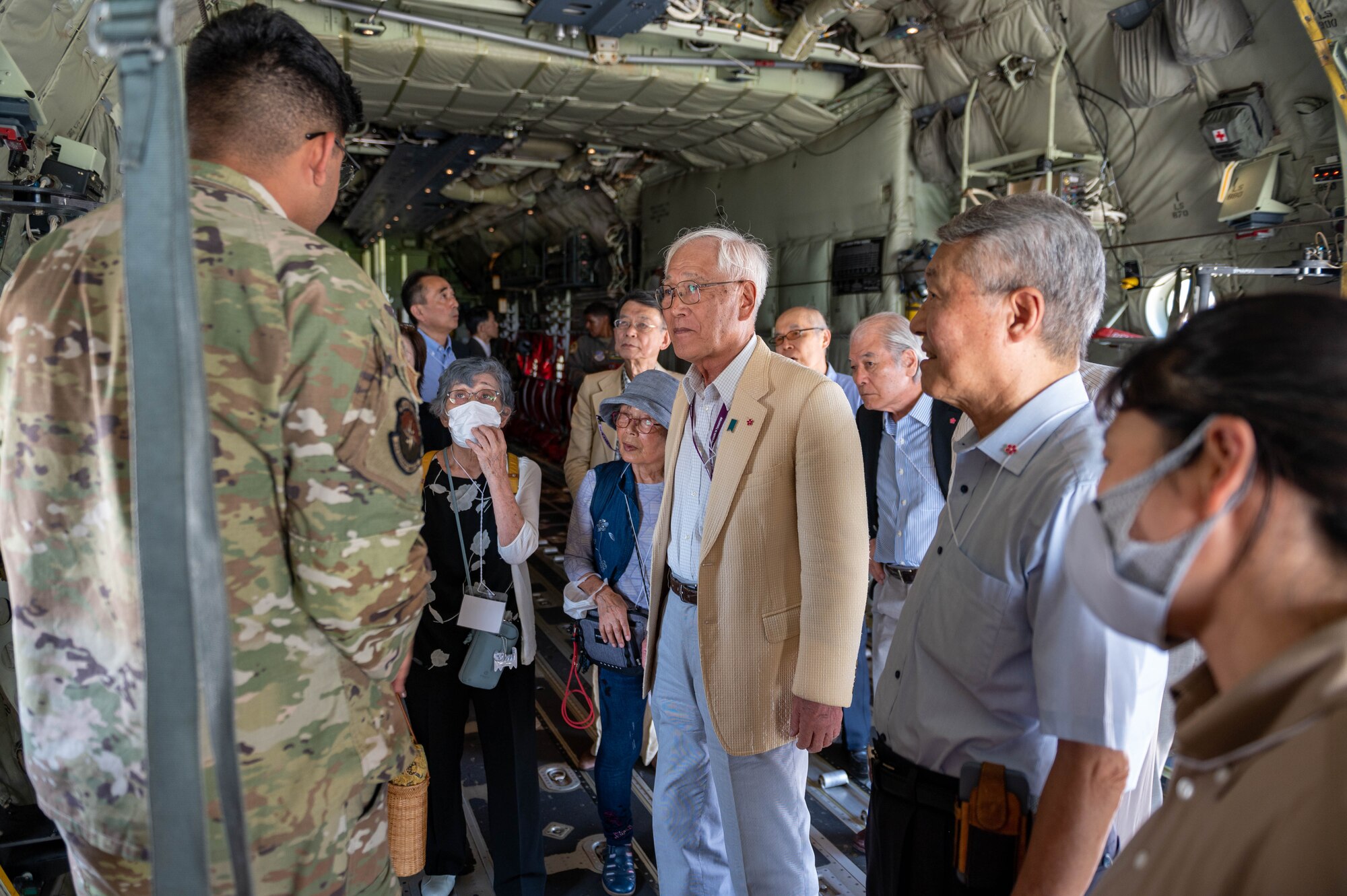 An American military member speaks to Japanese civilians in a C-130J Super Hercules.
