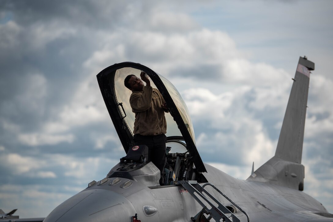 An airman cleans the canopy of a F-16 Fighting Falcon.