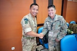 Maj Som Thulung, United Kingdom Armed Forces delegation, and Col. Pam Ellison, Hawaii Army National Guard, U.S. Armed Forces delegation, greet each other before the opening ceremony of the staff exercise portion of Super Garuda Shield 2023 on Aug. 31 in Surabaya Indonesia. The annual exercise has grown in scope and size since 2009.