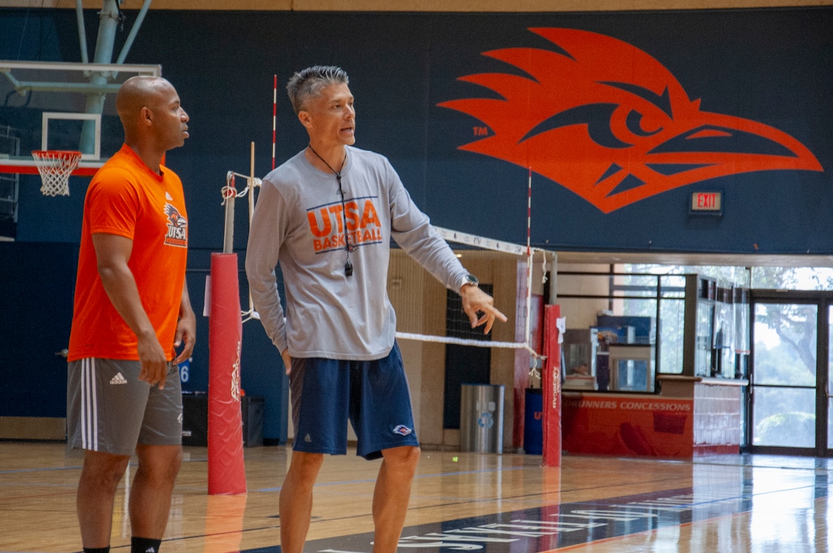 Darden and another member of coaching staff talk on sideline of basketball court