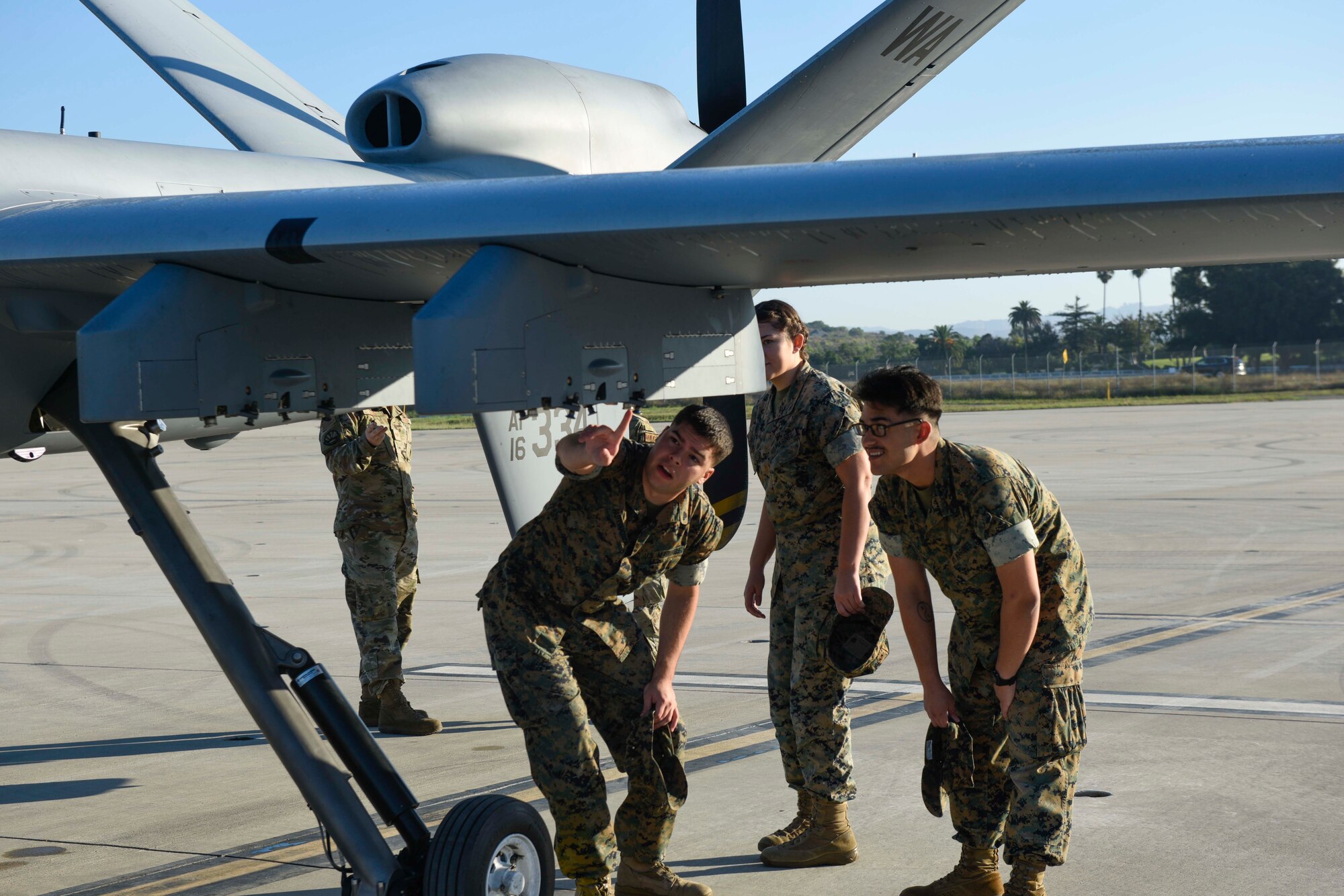 Three U.S. Marines examine an MQ-9 Reaper remotely piloted aircrafts wing.