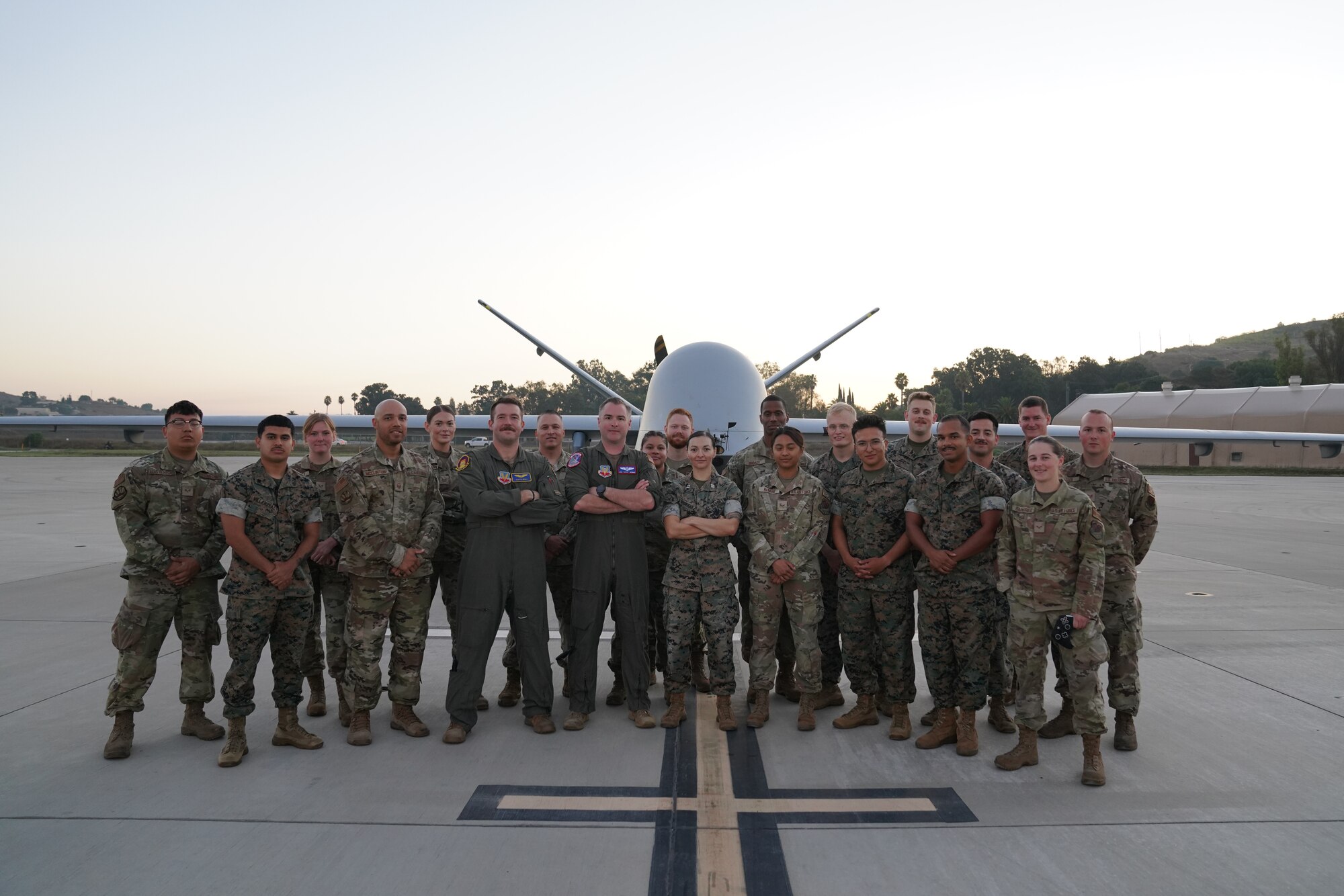 Airmen and Marines stand in front of an MQ-9 Reaper remotely piloted aircraft for a photo.