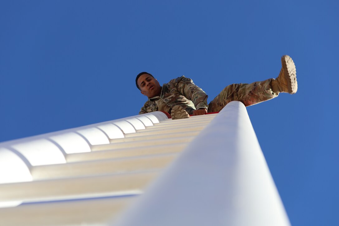 A soldier climbs over a ladder during daylight.