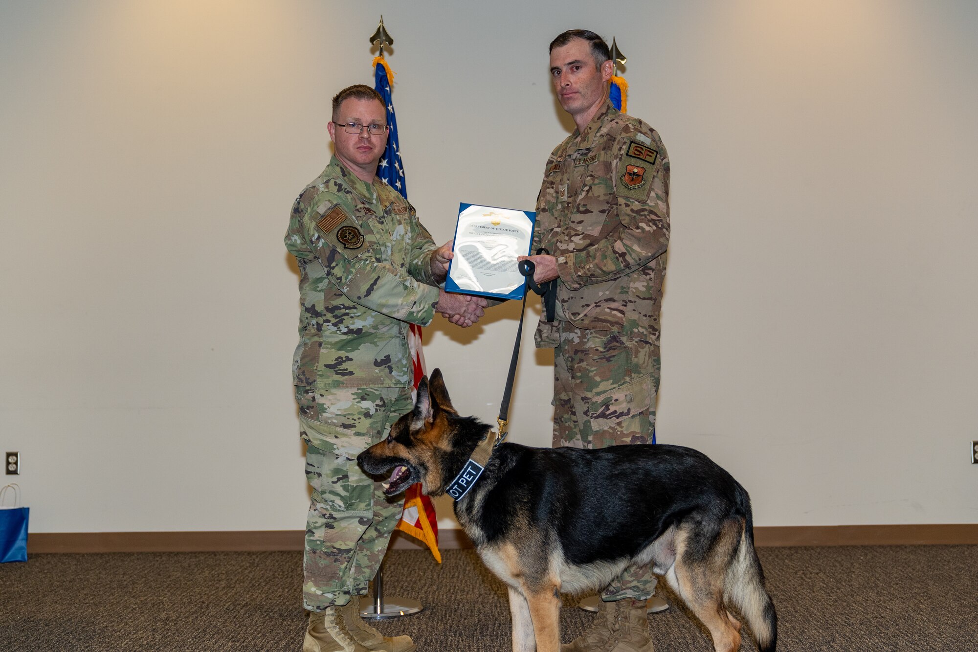 U.S. Air Force Maj. Shaun O’Dell, 81st Security Forces Squadron, defense force commander, and Technical Sgt. Garon Metcalf, 81st SFS, NCO in charge, pose with Gamma’s, 81st SFS, military working dog, retirement certificate during his retirement ceremony at Keesler Air Force Base, Mississippi, Aug. 25, 2023.