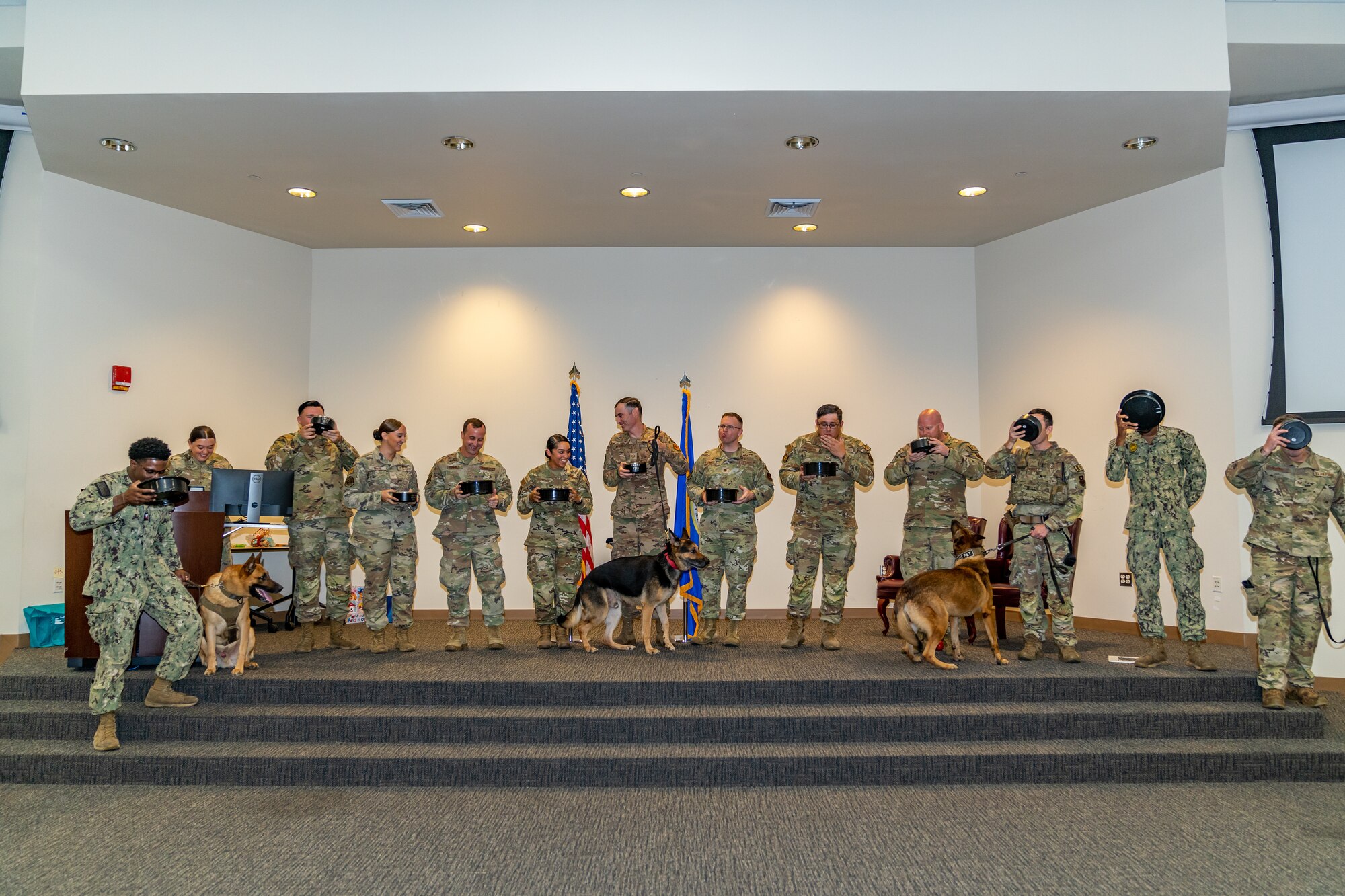 U.S. Air Force Airmen with 81st Security Forces Squadron and Navy Sailors “toast the bowls” to Gamma, 81st SFS, military working dog retired, during his retirement ceremony at Keesler Air Force Base, Mississippi, Aug. 18, 2023.