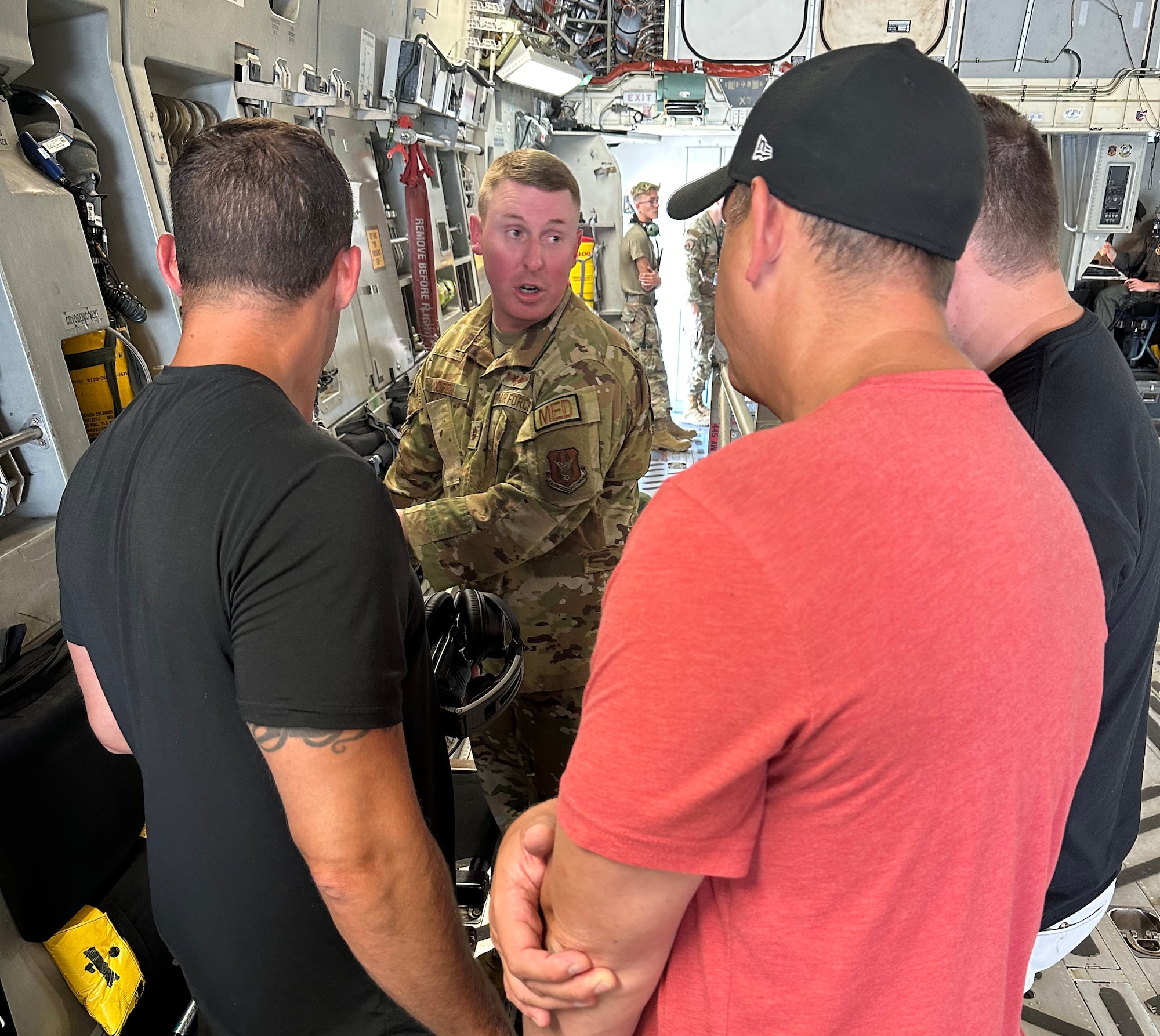U.S. Air Force Maj. Nathaniel Copen, center, 445th Aeromedical Evacuation Squadron director of operations, shows Rich Dotson, Garret Price and Matt O’Hara, DynastyNerds podcast, how the 445th Airlift Wing C-17 Globemaster III aircraft integrates well with the 445th AES mission at Wright-Patterson Air Force Base, Ohio, Aug. 23, 2023. The podcasters were shown the AES mission in Air Force Reserve Command as part of a visit to the base and Reserve wing. (U.S. Air Force photo by 445th Airlift Wing Public Affairs)(Photo taken with phone)