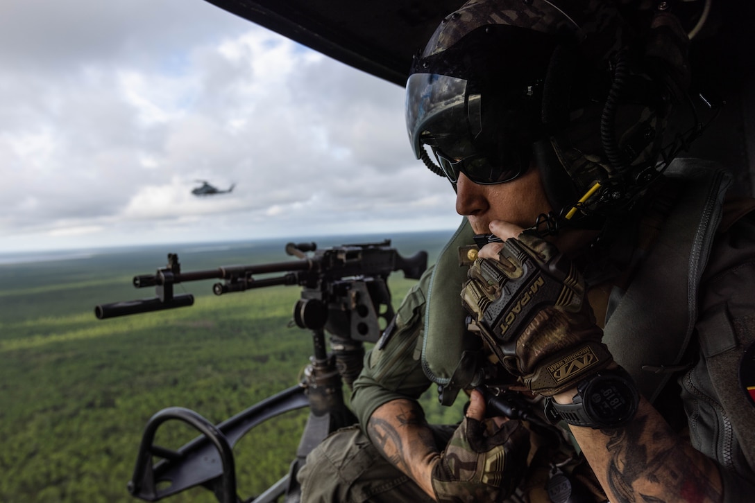 U.S. Marine Gunnery Sgt. Cody Meggs, a helicopter crew chief assigned to Marine Light Attack Helicopter Squadron 167, 2nd Marine Aircraft Wing, at Marine Corps Air Station (MCAS) New River, speaks into his headset during Exercise Mjolnir Strike 4-23, at Bombing Target 11 (BT-11), Piney Island, North Carolina, Aug. 17, 2023. Exercises such as Mjolnir Strike require multiple facets of coordination and planning to become whole. MCAS Cherry Point and its outlying ranges provide the support needed to effectively test and train, bringing out the full realization of Mjolnir Strike and more. (U.S. Marine Corps photo by Cpl. Jade Farrington)