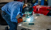 A person in a blue shirt is welding aluminum