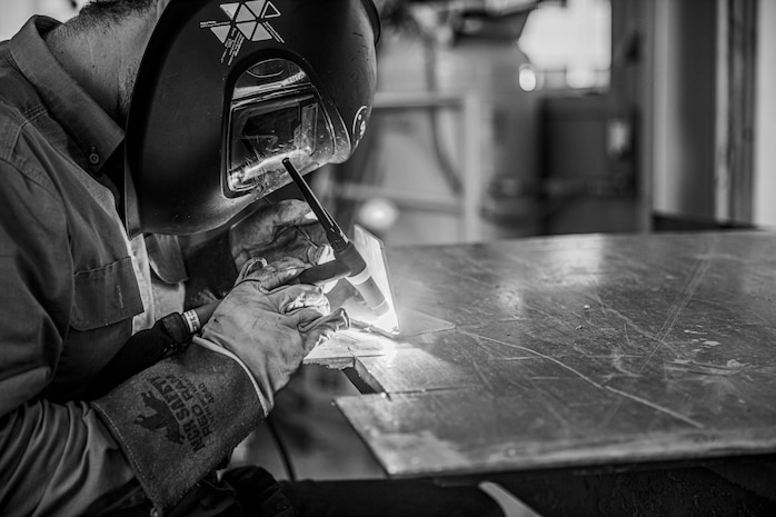 A person in a blue shirt is welding aluminum