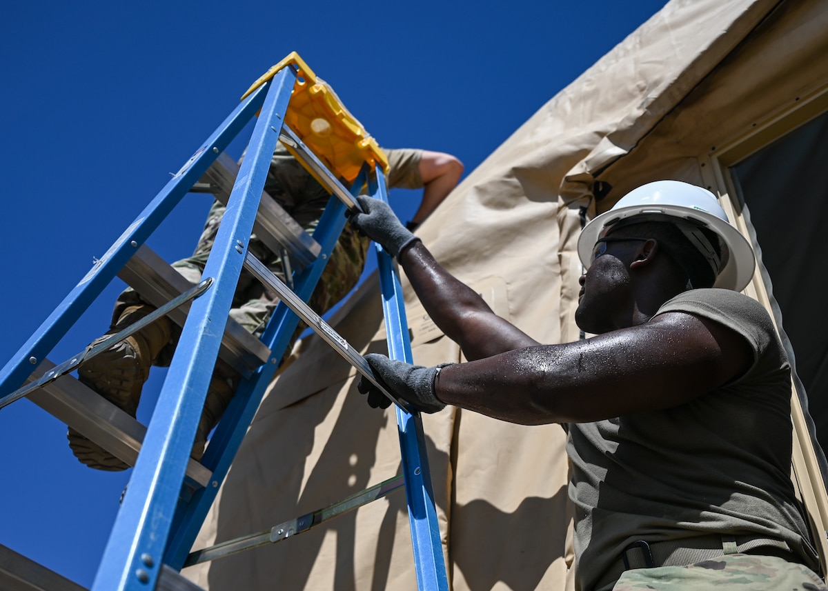 A photo of a person in a military uniform holding a ladder.