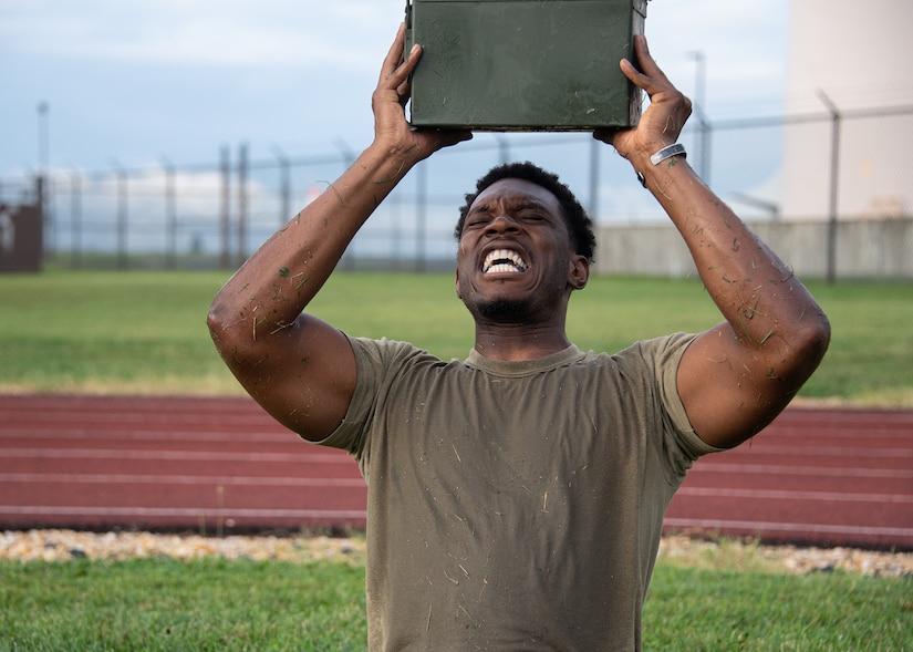 A man lifts an ammo can over his head.