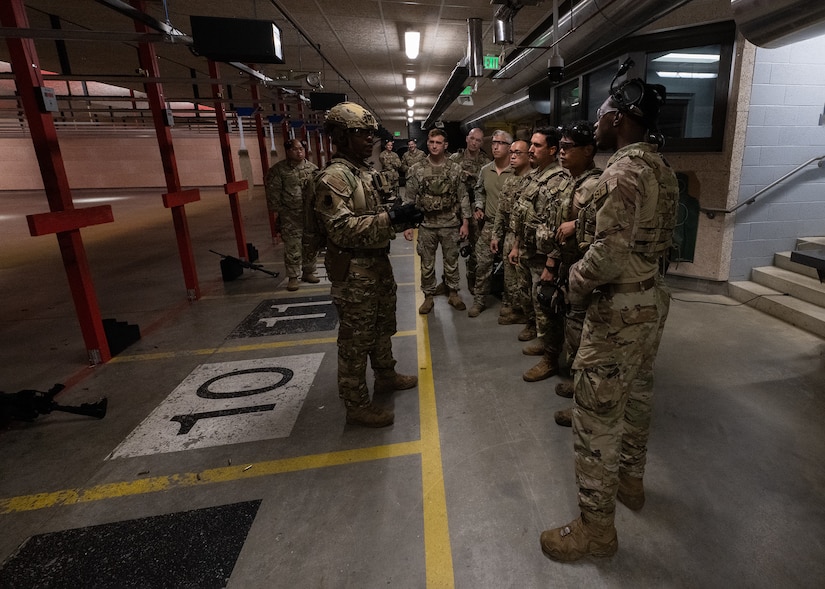 Military members in uniform talk at a gun range.