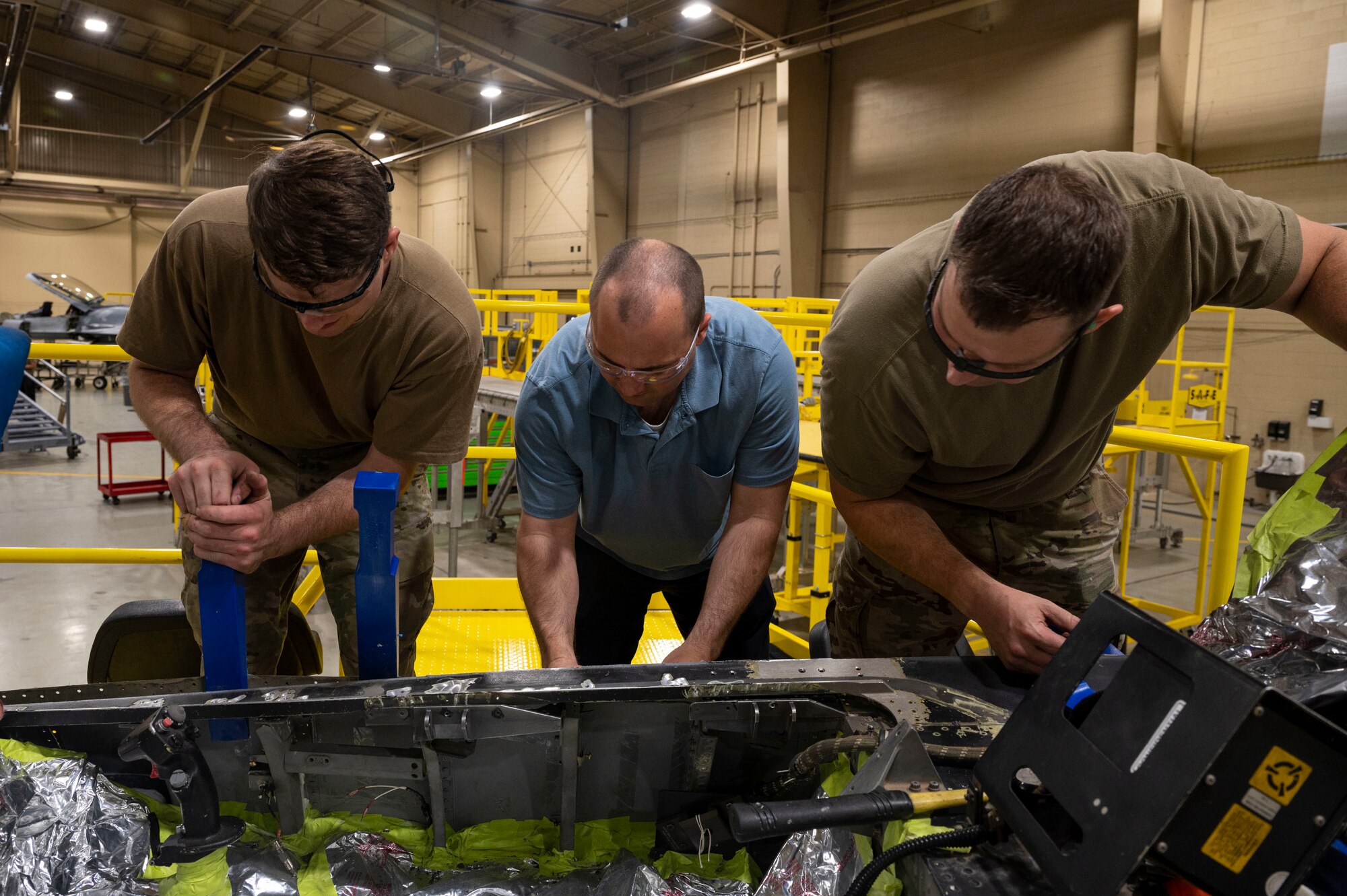 U.S. Air Force Staff Sgt. Braden Gibson, 49th Equipment Maintenance Squadron sheet metal shift lead, left, removes the panel of an F-16 Viper with Tyler Brooke, 309th Software Engineering Group F-16 structural engineer, center, and U.S. Air Force Tech. Sgt. Robert McPherson, 49th EMS aircraft structural maintenance noncommissioned officer in charge, at Holloman Air Force Base, New Mexico, Aug. 1, 2023.