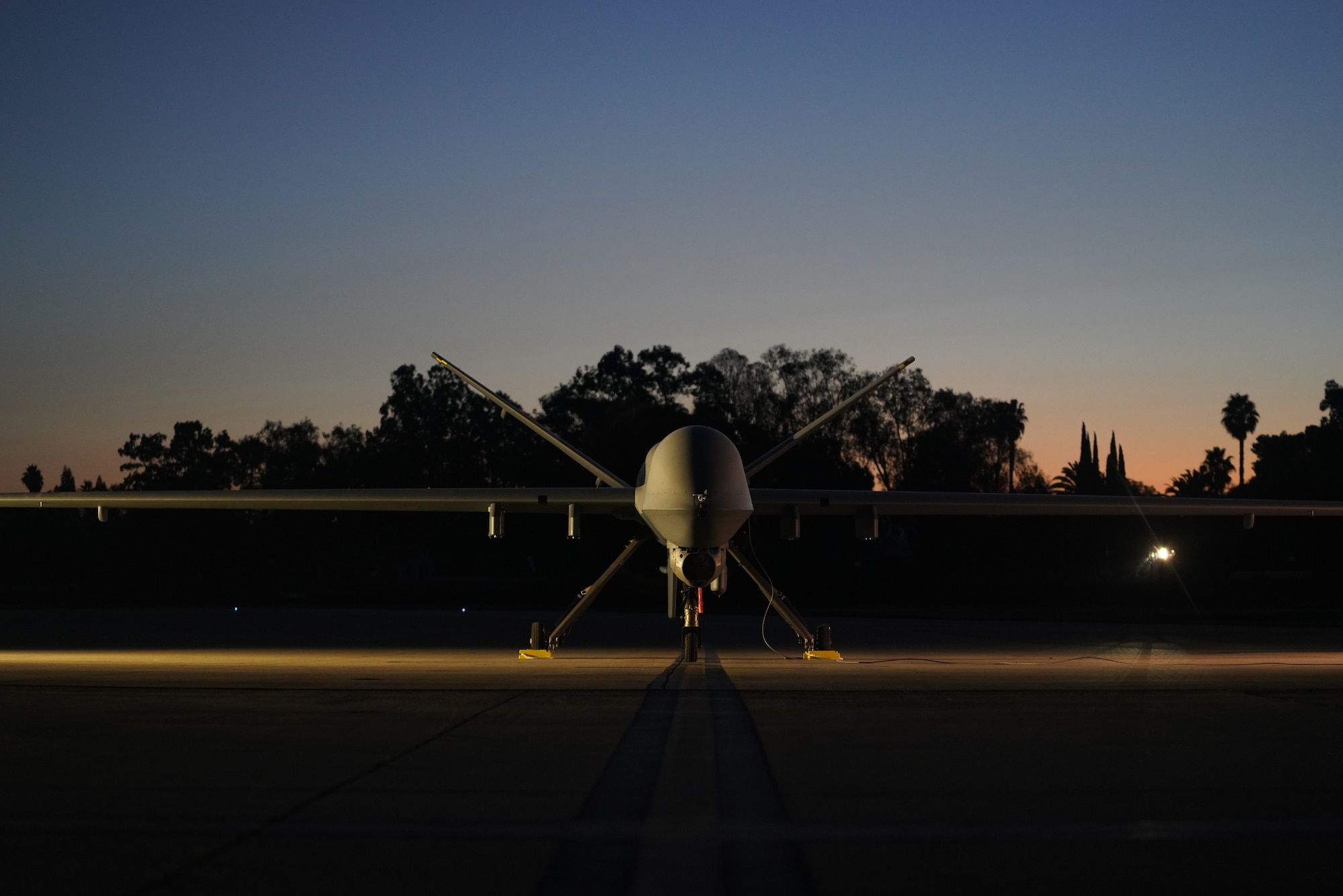 An unmanned aircraft sits on a flight line during sunset.