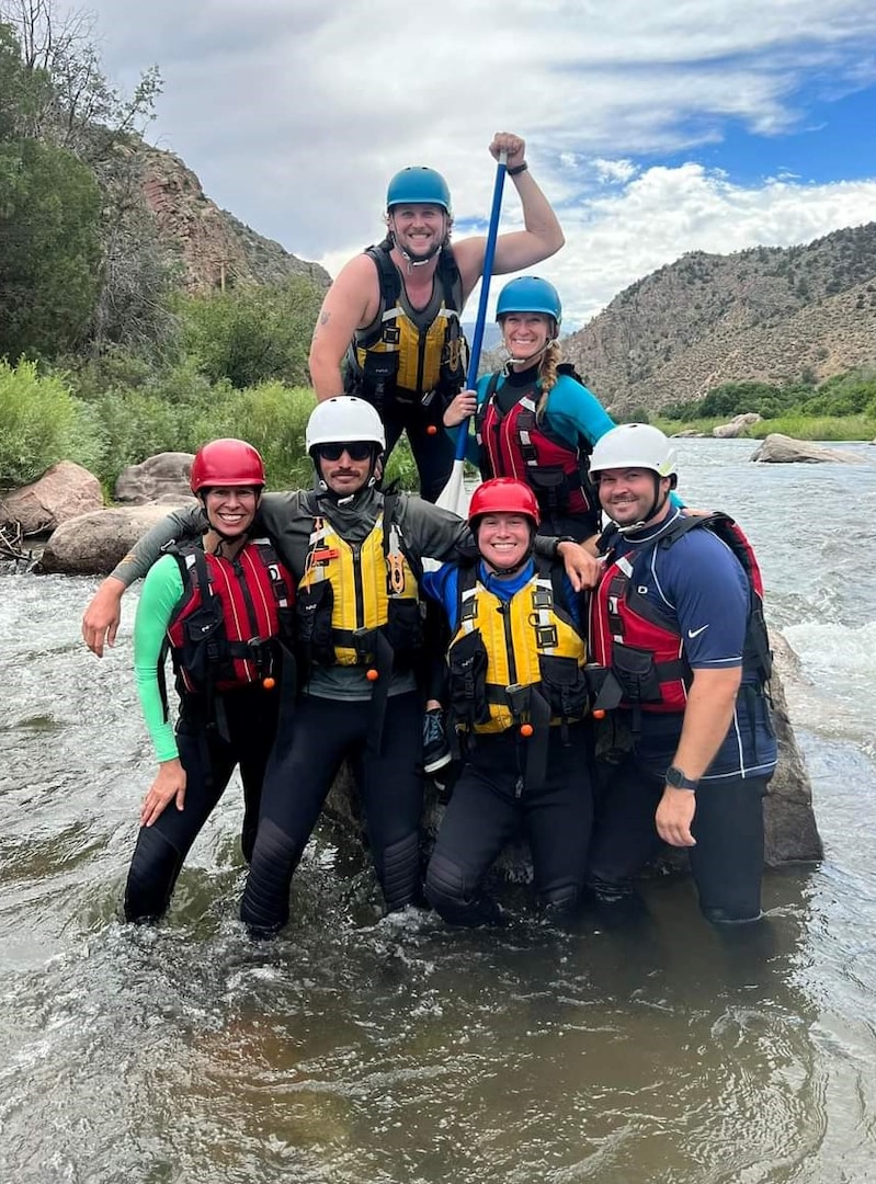 six people pose for a photo in knee deep water